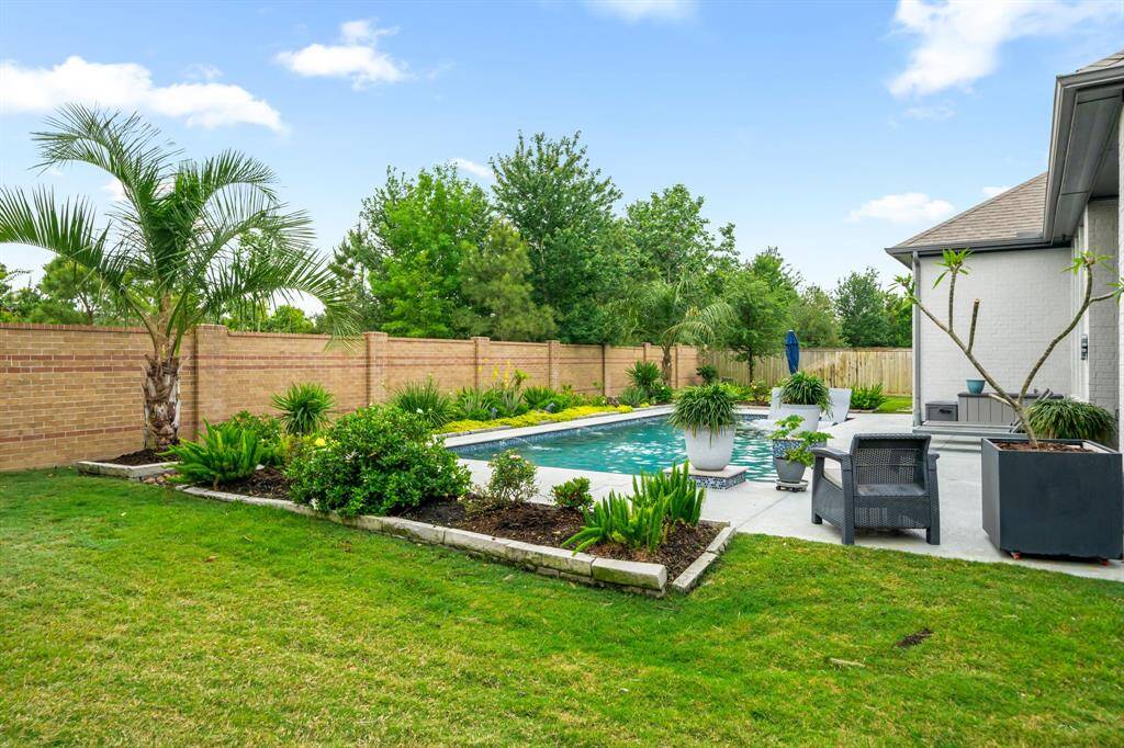 Custom-designed landscaping with high-end perennials and palms offers a beautiful landscaping backdrop to the pool, which is complemented by this brick wall. The wall was recently power washed. This home is so very well maintained inside and out! The owners have left no stone unturned.