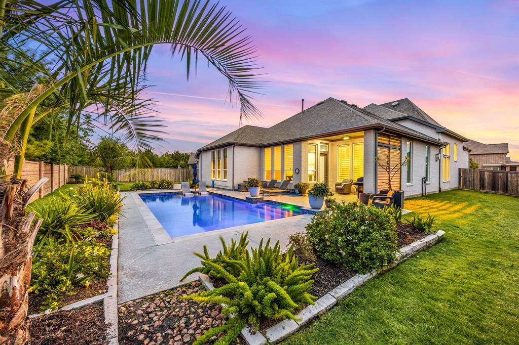 Another view of the rear elevation with extra grassy areas on each side of the home. This home comes with gutters and a well-designed landscaping drainage design.