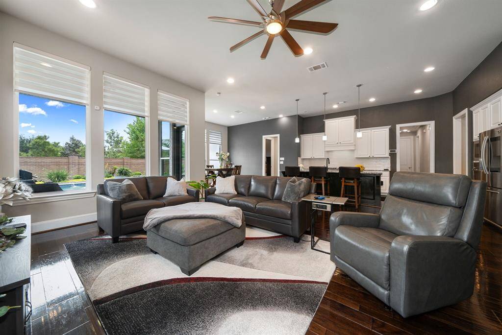 A wall of large, fixed windows in the living area makes this space feel bright and airy. Electronic blinds can be adjusted for privacy or for an unobstructed view to the beautiful outdoors. The modern ceiling fan with LED lighting complements this space for more energy-efficient and comfortable living.