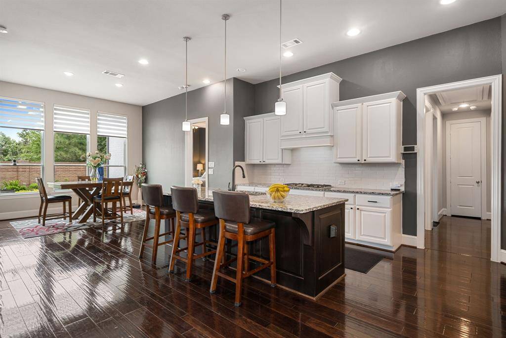 The kitchen is equipped with stainless steel appliances, a sensor faucet, stainless steel farm sink, granite countertops, a 5-burner stovetop, wall oven, and smart refrigerator (not pictured in this shot). Nothing to upgrade, just bring your pots and pans to serve up your favorite meals. The hallway leads to 2 bedrooms and a full bath.