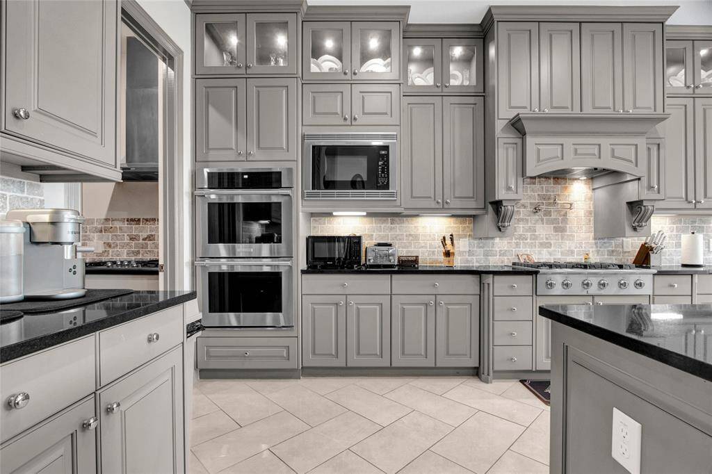 Elevate your culinary experience with premium stainless steel appliances, featuring a double oven, built-in microwave, and a professional-grade gas cooktop with a custom vent hood.