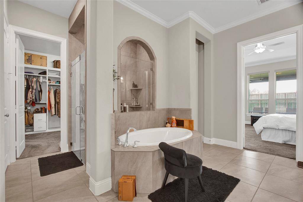 Indulge in relaxation with a deep soaking tub set in an elegant arched niche, complemented by a spacious walk-in shower featuring stylish tilework and convenient built-in shelving.