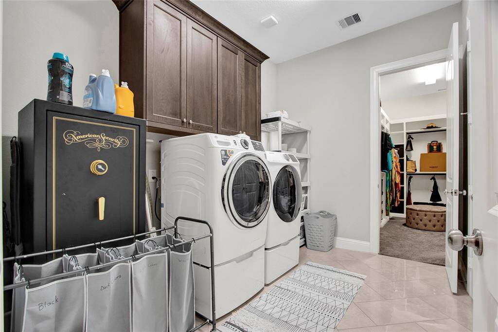 Spacious utility room with abundant cabinetry and discreet access to the primary closet.