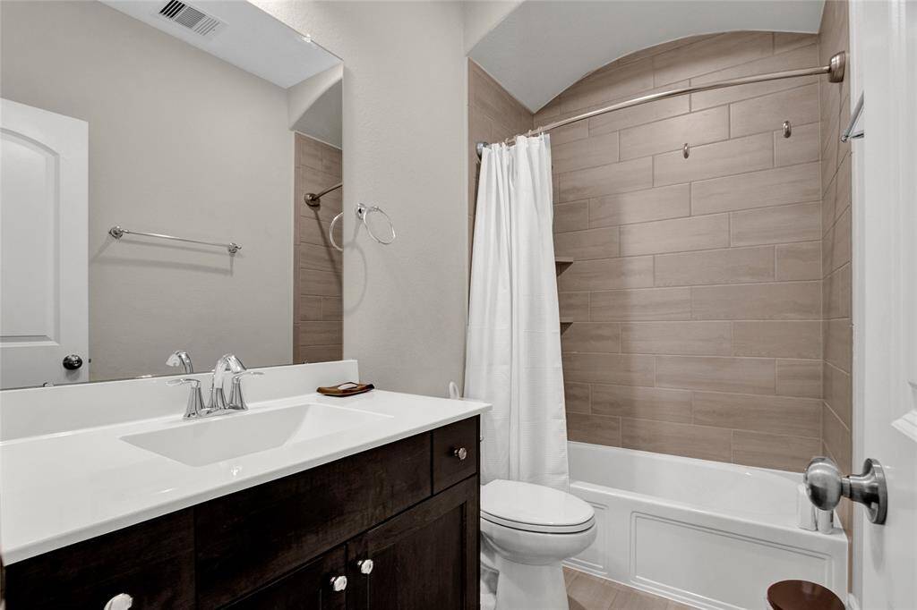 Elegant fourth full bath with rich cabinetry, wood-look tile, and a tub/shower combo—ideal for guests or daily use.