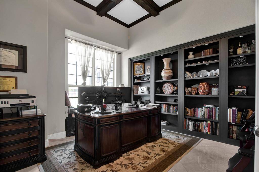 An elegant home office featuring built-in bookshelves and rich ceiling beams, perfect for work or reflection.