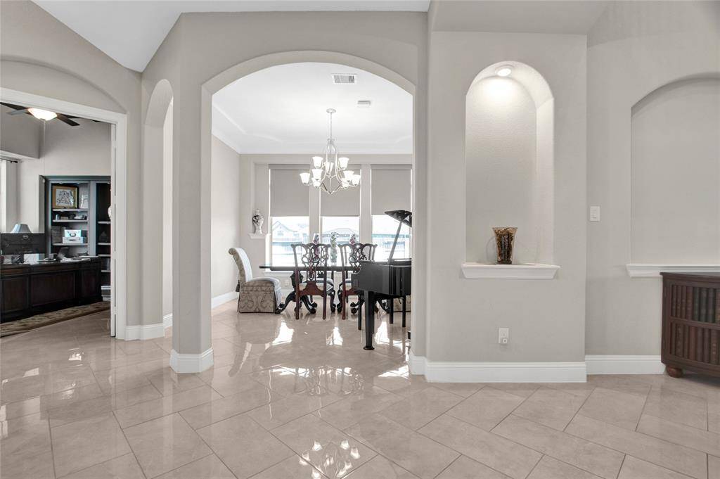 Elegant crown molding, tray ceilings, and polished tile floors enhance the spacious layout, perfect for large dining sets.