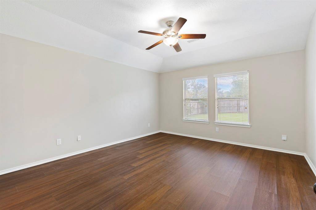 Primary suite privately tucked away with hard surface flooring and ceiling fan.