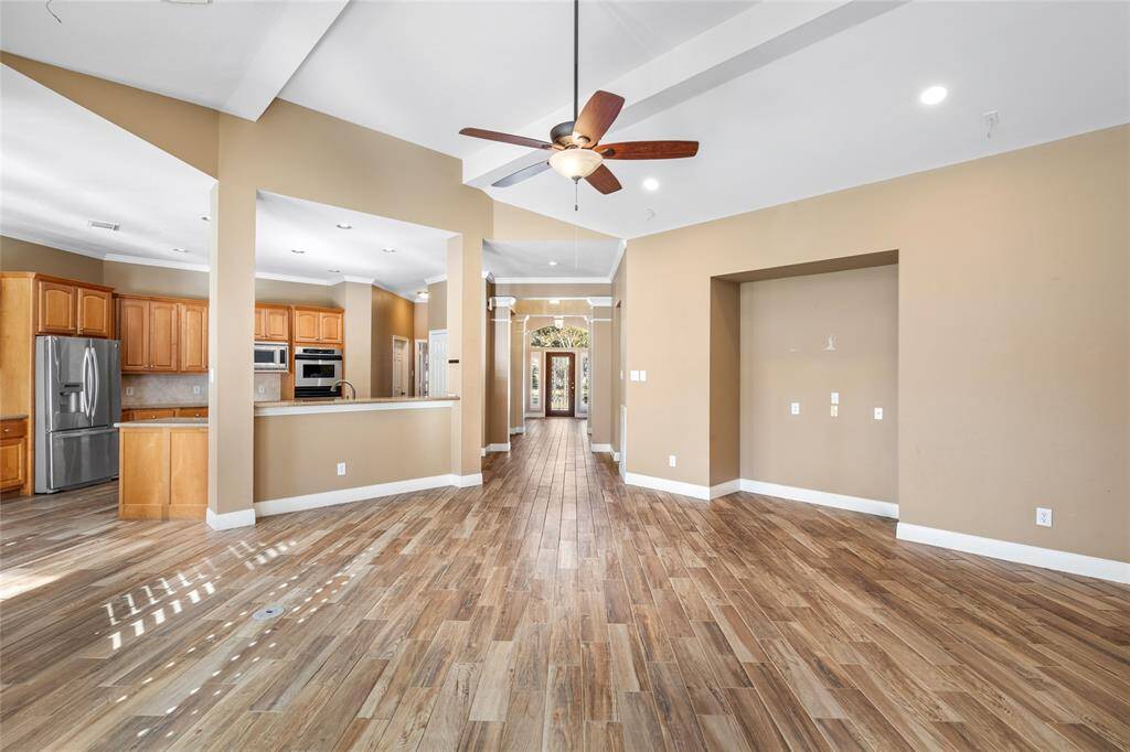 From this vantage point, you can see the spacious living room and kitchen, both of which are bathed in natural light from the wall of windows that offer a stunning view of the backyard and pool. The seamless transition between the indoor and outdoor spaces creates an ideal setting for relaxation and entertaining.