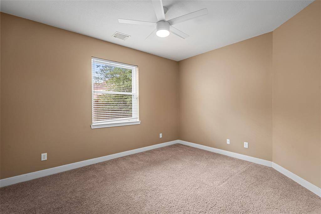 Another spacious secondary bedroom, featuring soft carpet floors and light earth-toned paint that creates a calm, neutral atmosphere. This room is perfect for a variety of uses, from a guest room to a home office, offering both comfort and versatility.