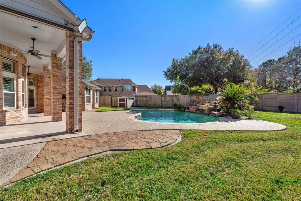 This view captures the serene pool and the inviting covered back porch, offering the perfect setting for outdoor relaxation and entertaining. Whether you’re lounging by the pool or enjoying a meal on the porch, this space provides a seamless blend of comfort and outdoor living.