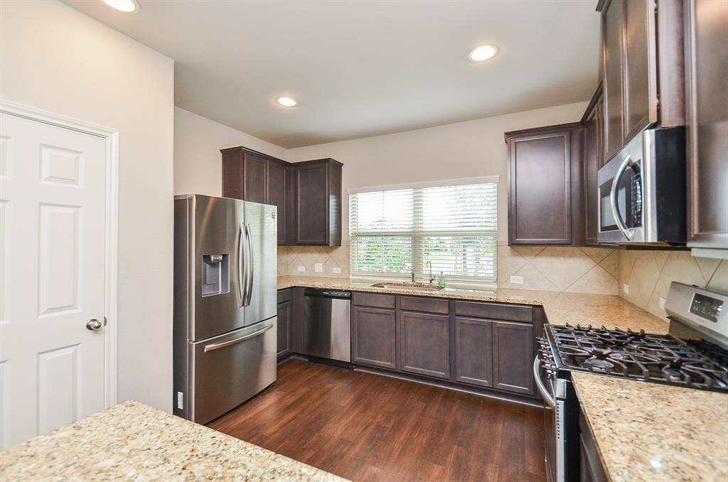 A roomy farmhouse style stainless steel sink sits below huge double windows.