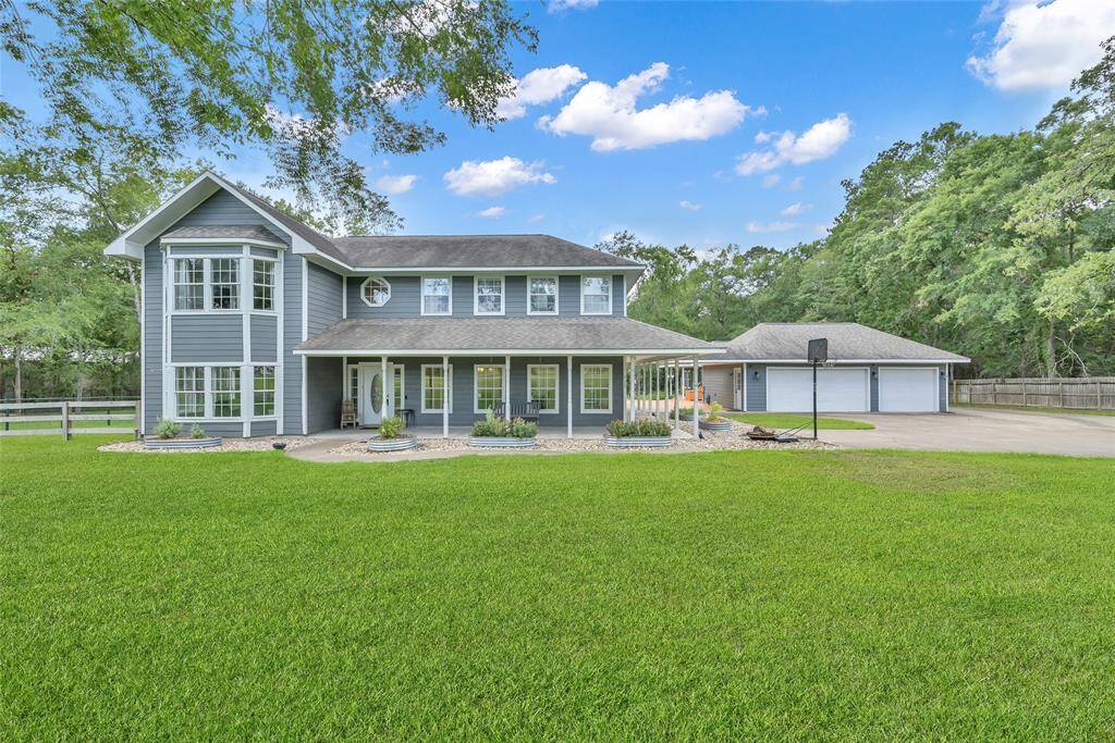 Daytime curb appeal at its finest! This traditional gray farmhouse-style home is perfectly framed by lush lawn and mature trees.