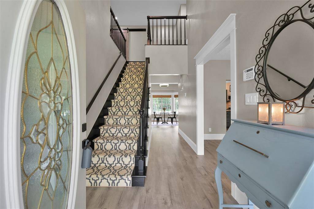 A warm hello from the entryway! Gorgeous leaded-glass front door opens to wood floors, fresh neutral tones, and an elegant staircase.