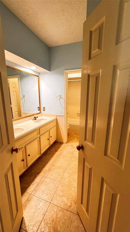 second bathroom with double sinks and storage