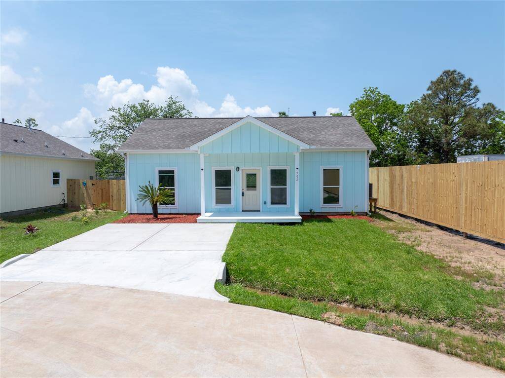Charming single-story light blue house with a welcoming front porch. Features a neatly manicured lawn, white driveway, and fenced backyard. Ideal for comfortable living.