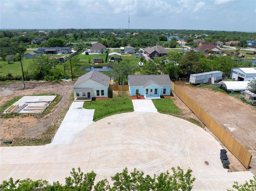 This aerial photo showcases a pair of charming single-story homes with fresh landscaping, located on a quiet cul-de-sac. The surrounding area features spacious lots, a mix of developed and under-construction properties, and is set in a green, suburban neighborhood.