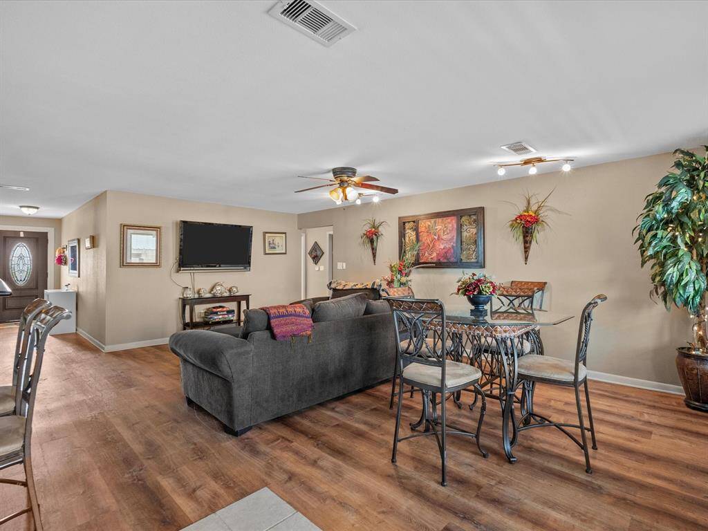 This inviting living space features an open layout with wood flooring, a cozy seating area, and a dining table. It includes modern decor, ceiling fans, and ample natural light, creating a warm and welcoming atmosphere.