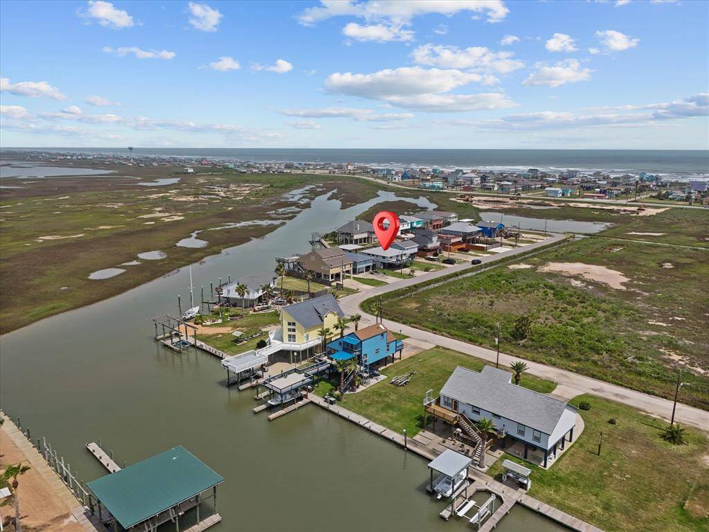 This aerial photo showcases a charming waterfront home with a dock, located along a peaceful canal. The property is surrounded by other similar homes and offers serene water views, making it ideal for those seeking a tranquil lifestyle with easy access to boating and outdoor activities.