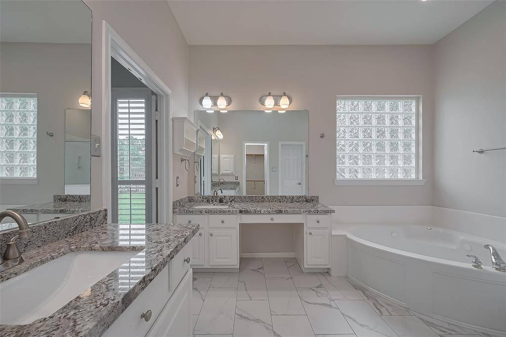 Beautiful primary bathroom is well-appointed with desirable features, two separate granite sink tops, tile with marble style looking and a relaxing jetted tub. Including direct access to a spacious walk-in closet.