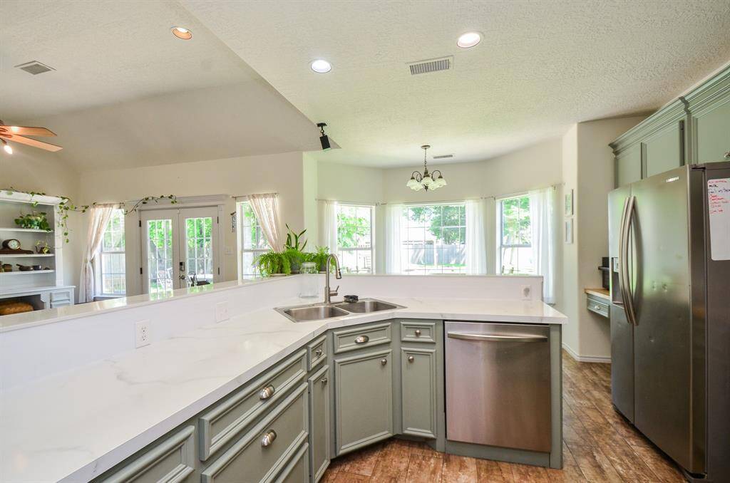 KITCHEN WITH STAINLESS APPLIANCES, NEUTRAL COUNTERTOPS AND WOOD PAINTED CABINETS