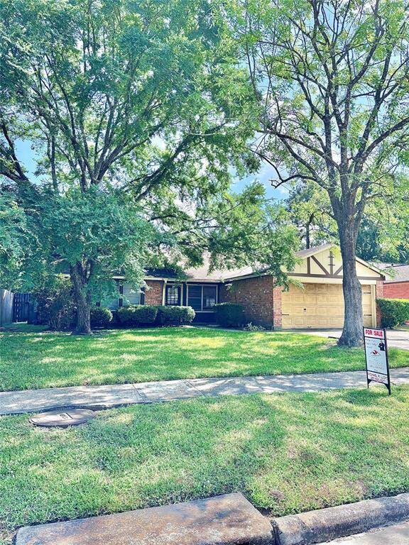 Charming single-story home with a brick exterior, two-car garage, and mature trees providing ample shade. The well-maintained front yard enhances curb appeal.