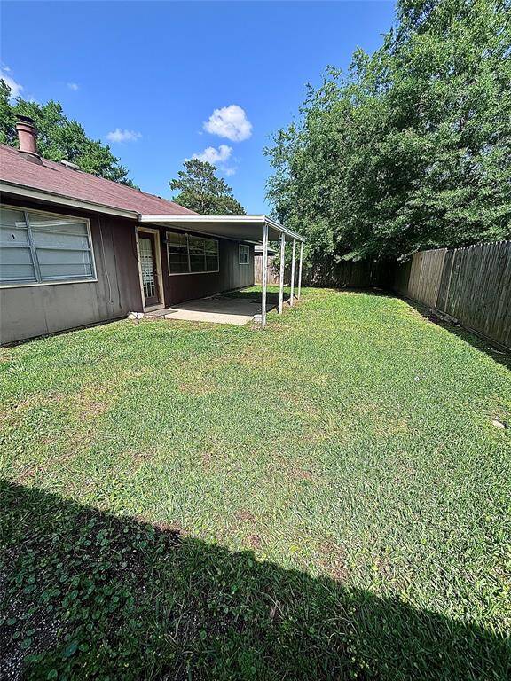 Cozy backyard with a covered patio area, bordered by a wooden fence and mature trees, offering privacy and shade.