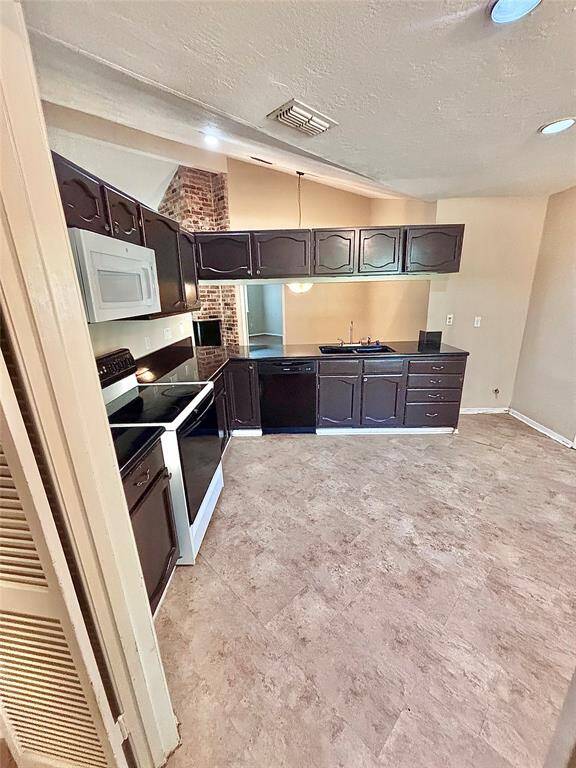 This photo shows a cozy kitchen with dark cabinetry and tile flooring. It features a stove, microwave, and ample counter space, creating a functional cooking area.