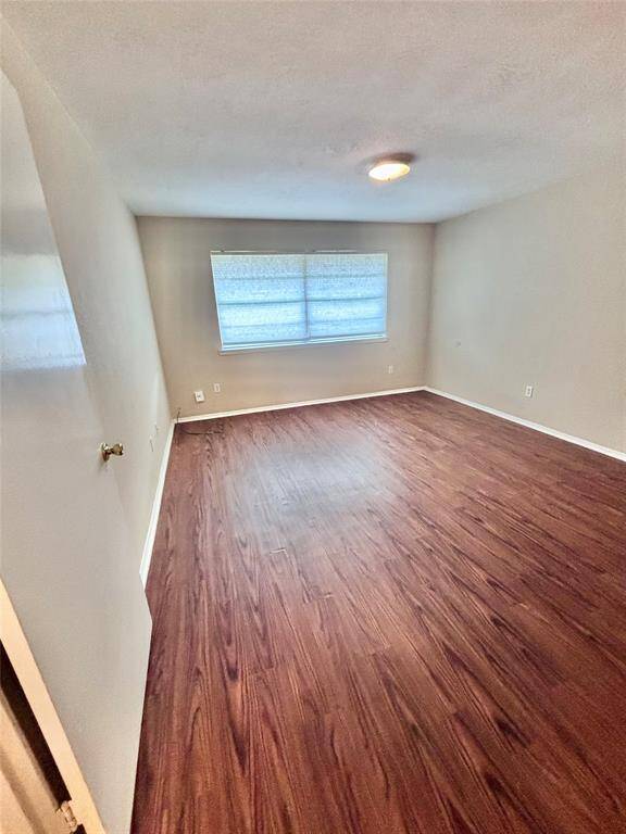 This Primary bedroom features wood flooring, neutral walls, and a large window with blinds, providing ample natural light.