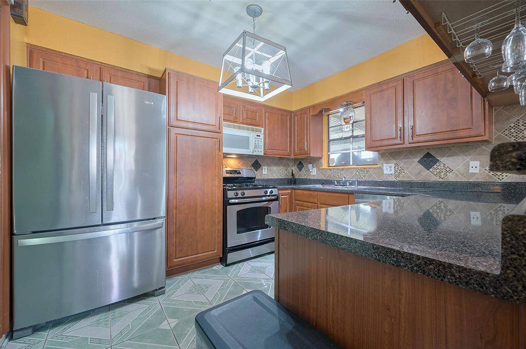 The barn doors open into a charming kitchen (10'10" x 9'7") with warm wood cabinets and stylish granite-look laminate countertops. Updated light fixture brightens the space, and upgraded cabinet hardware adds a modern touch. A perfect blend of cozy and contemporary!