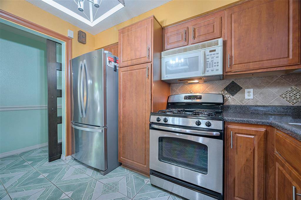 The kitchen includes a Whirlpool stainless steel refrigerator with side-by-side doors and a bottom freezer for easy access. Just to the right, a spacious pantry offers convenient storage for all your kitchen essentials, keeping everything neatly organized.
