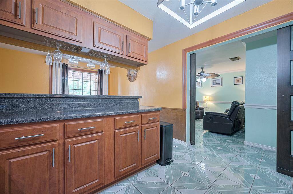 Opposite the refrigerator and gas range, a long cabinet offers plenty of additional storage space and countertop workspace. The upper cabinets feature under-cabinet organizers, perfect for displaying wine glasses or other stemware. On the opposite side, a long high-bar breakfast bar separates the kitchen from the eat-in breakfast area, creating a great spot for casual dining.