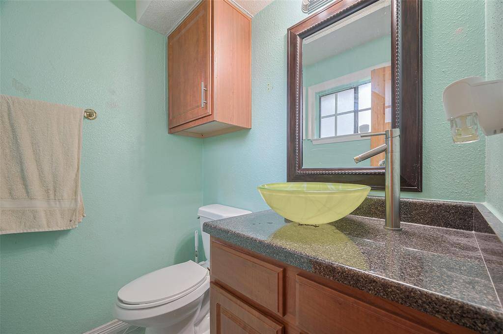 The owner's bathroom conveniently features a vanity with a vessel sink, an upgraded sleek faucet, and a decorative mirror. Updated lighting adds a modern touch, while the commode and over-commode storage cabinet provide practical storage. A frosted window ensures privacy, making this space both functional and stylish.