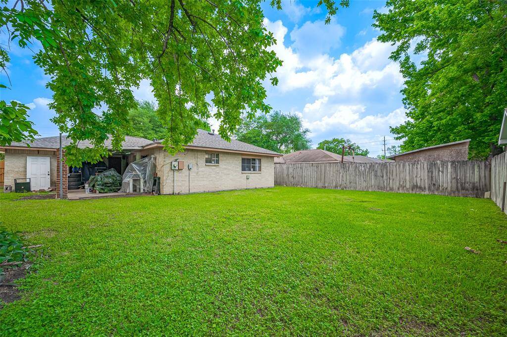 The view from the back of the house shows beautiful brick on all four sides, offering both durability and charm. With the roof replaced in 2023, you can enjoy peace of mind for years to come. On the left side, a covered concrete patio invites you to unwind, enjoy the outdoors, or entertain guests in a relaxed, cozy setting.
