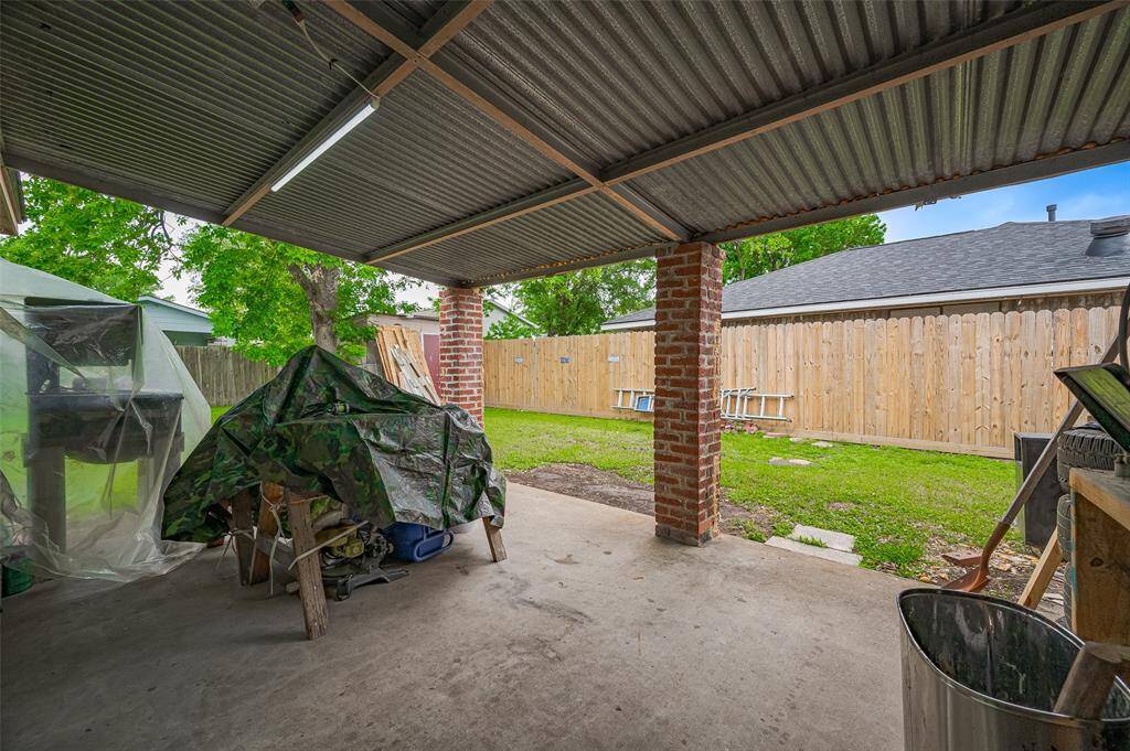 Keep this space as a backyard workshop or transform it into a great outdoor entertainment area. The covered patio is currently well-lit with shop lights and houses woodworking equipment, showcasing its potential for your family's handyman or artisan. This versatile space is perfect for enjoying the outdoors, even during inclement weather. Whether you're watching children play, grilling, or hosting outdoor barbecues with friends and family, it offers endless possibilities for relaxation and togetherness.