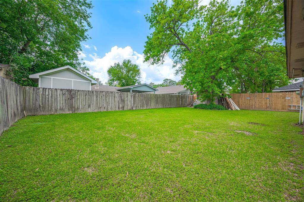 The backyard is fully fenced with a wood privacy fence, offering a sense of security and seclusion. A tree in the far right-hand corner adds charm and shade. There's plenty of room for children and the family dog to run and play, making it an ideal space for outdoor fun and relaxation.