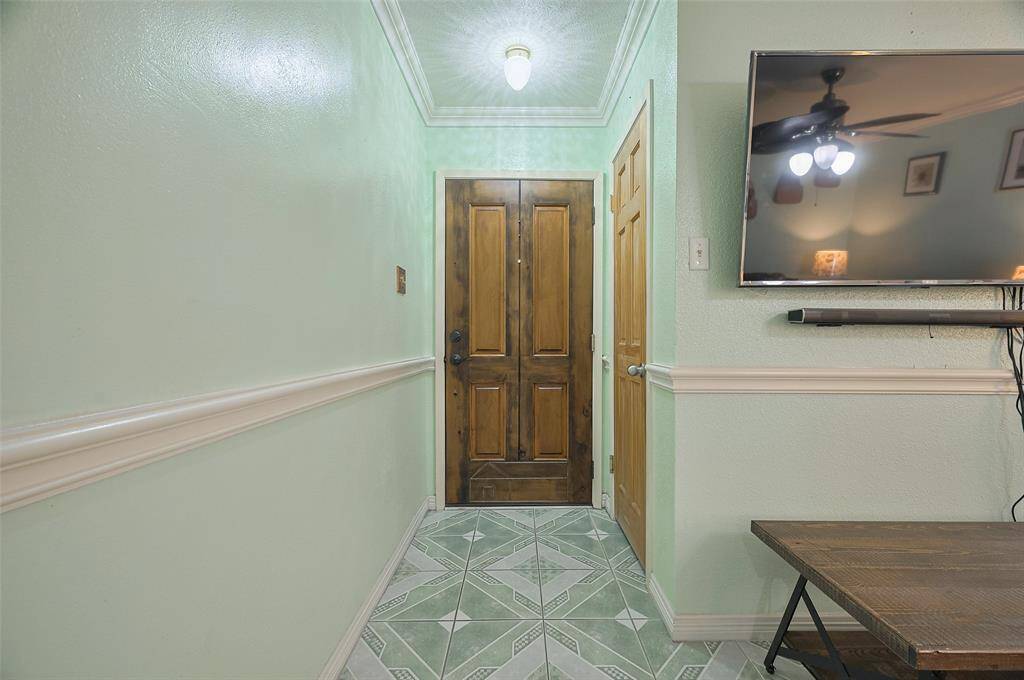 The front door opens into a welcoming foyer with a tile floor, crown molding, and chair-rail accents. A convenient coat closet offers extra storage. Throughout the home, the owner has replaced all doors with solid wood, ensuring no hollow core doors — adding a touch of quality and craftsmanship.