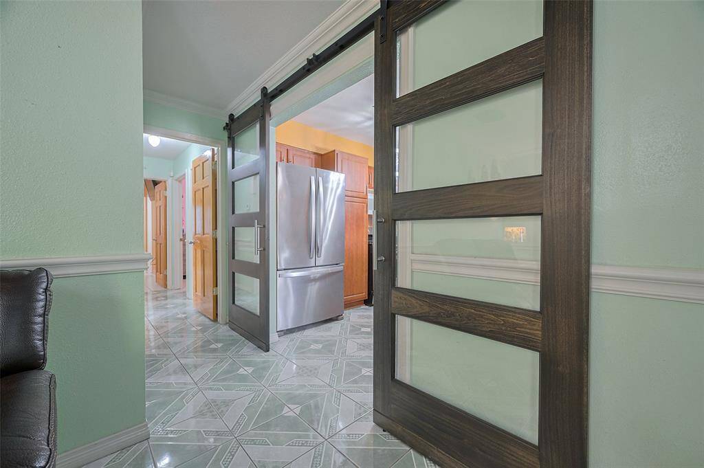 A gorgeous pair of sliding glass and wood barn doors separates the kitchen from the living room, offering a modern, sleek design and helping to control noise between the two spaces. A hallway leads to three bedrooms and 1½ baths, with a hallway door providing added privacy between the living and sleeping areas.