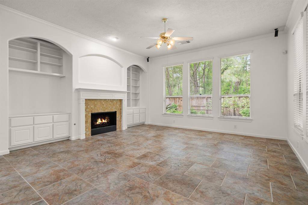 Spacious living area has tile flooring, crown molding, bookshelves and a fireplace!