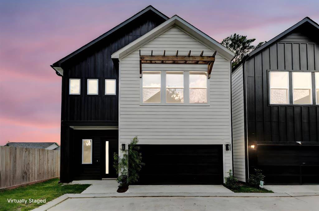 Modern two-story home with a sleek, contrasting exterior featuring black and white siding. It includes large windows, a double garage, and minimal landscaping. Ideal for contemporary living.
