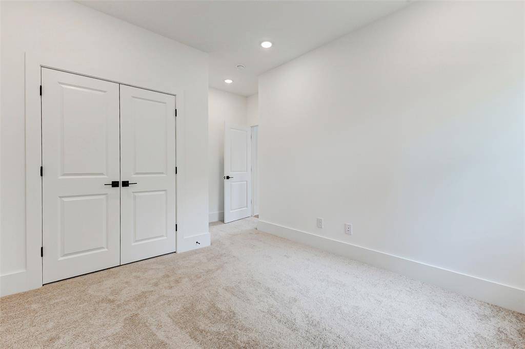 This photo showcases a bright, spacious room with neutral-colored carpet and white walls. It features a double-door closet and recessed lighting, creating a clean and modern look.