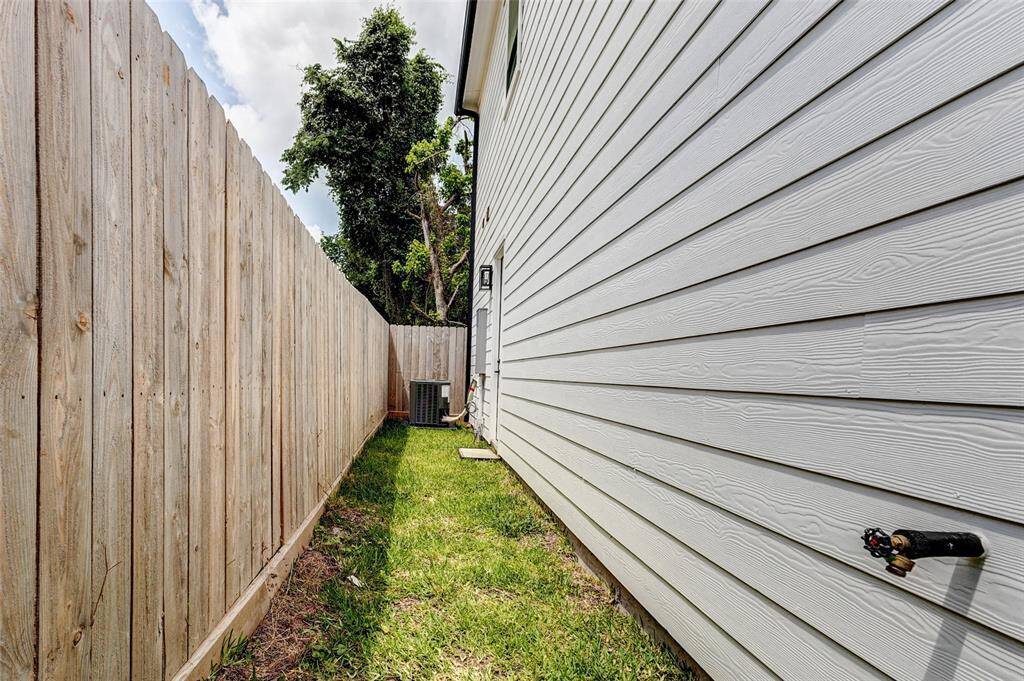 A charming side yard features a lush grass area, bordered by a wooden fence and the home's exterior wall.