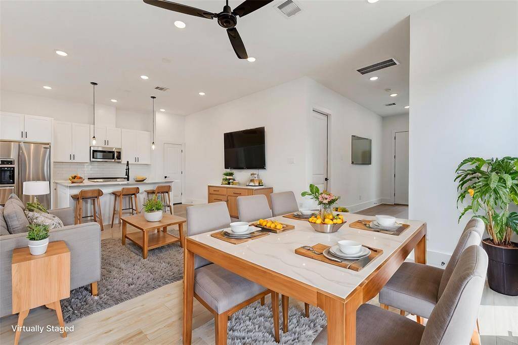 This modern, open-concept living space features a sleek kitchen with stainless steel appliances, an island with bar seating, and a cozy dining area. The living room is spacious, with abundant natural light and contemporary furnishings.Virtually staged