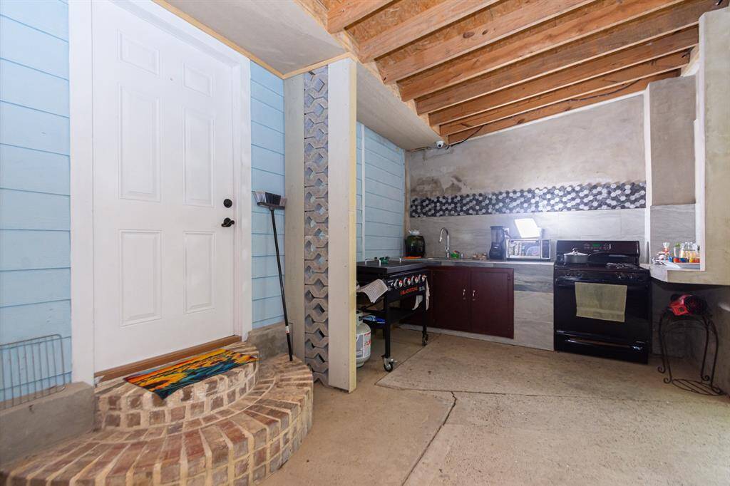 As you step outside to the covered back porch and you have an outdoor kitchen with stove, sink and mini fridge!  The stove is fueled by a hidden propane tank.