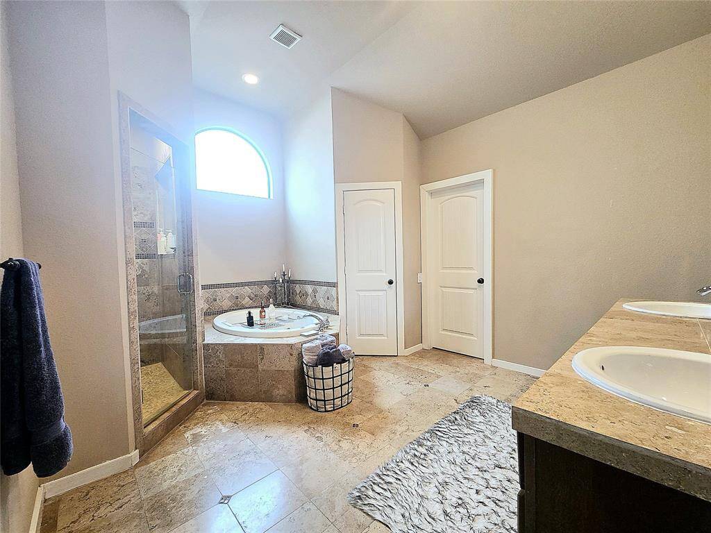 A spa-like primary ensuite bath featuring a large soaking tub and a walk-in shower, both adorned with exquisite custom tile work for a luxurious retreat.