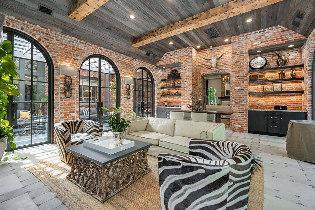 The Outdoor Living Area is a favorite w/ its Reclaimed Barn Wood Ceiling. The floor beautifully designed with Limestone and Reclaimed European Concrete Tiles! Notice all the Arched double doors leading to the outdoor grounds.