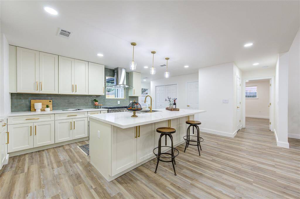 The island kitchen is a stunning focal point, fully renovated with Quartz countertops and a modern green subway tile backsplash that adds a pop of color. The spacious island provides ample counter space for meal prep and doubles as a casual dining area with seating.