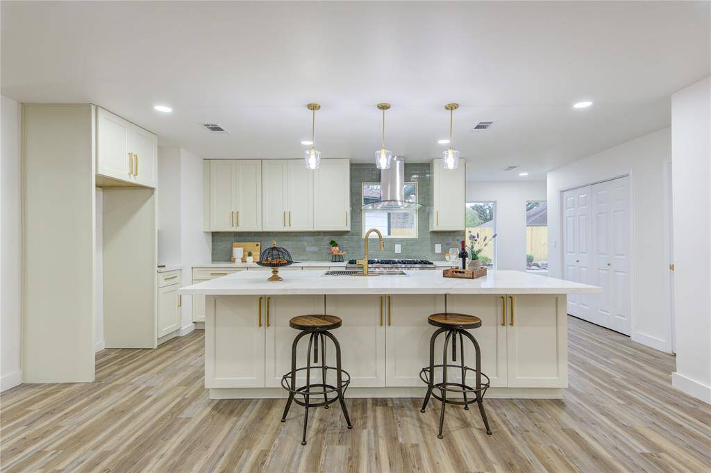 The breakfast bar on one side of the island is perfect for casual meals, offering seating for family and guests while allowing for easy conversation with the cook. The Quartz countertops extend across the island, complemented by the sleek green subway tile backsplash.