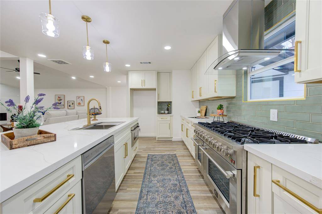 The island kitchen has been completely renovated with Quartz countertops, a green subway tile backsplash, and custom cabinetry that provides both style and functionality. The 6-burner Professional Series Gas Range is perfect for the home chef, while the open layout allows for seamless movement between the kitchen, dining, and living spaces.