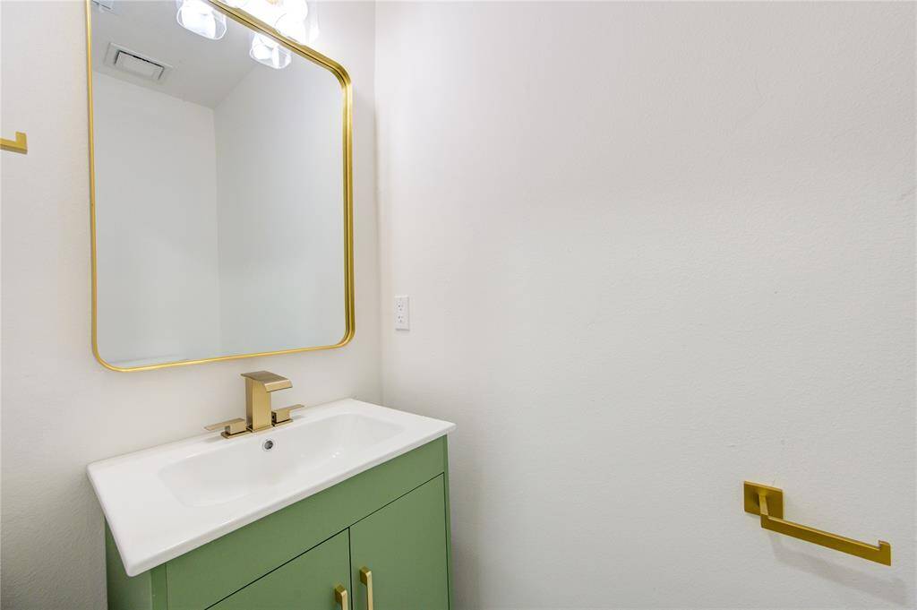 The powder room is a beautifully designed space featuring a trendy green vanity cabinet, adding a bold and modern touch to the home’s aesthetic.