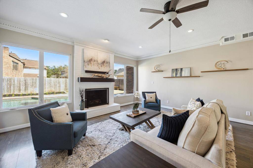A cozy fireplace with a striking floor-to-ceiling brick hearth anchors the space, making it perfect for relaxing evenings or lively gatherings.